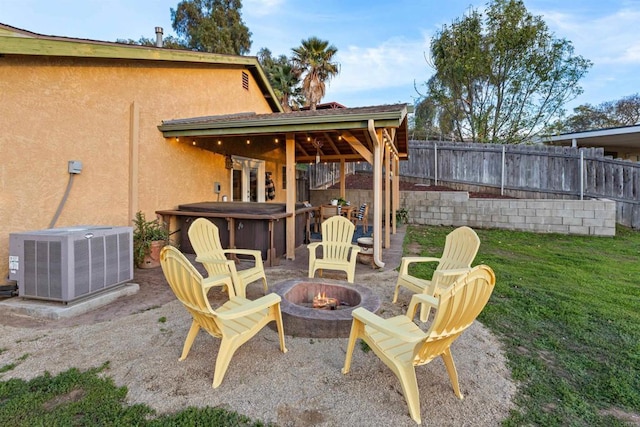 view of patio featuring central air condition unit, a jacuzzi, fence, and a fire pit