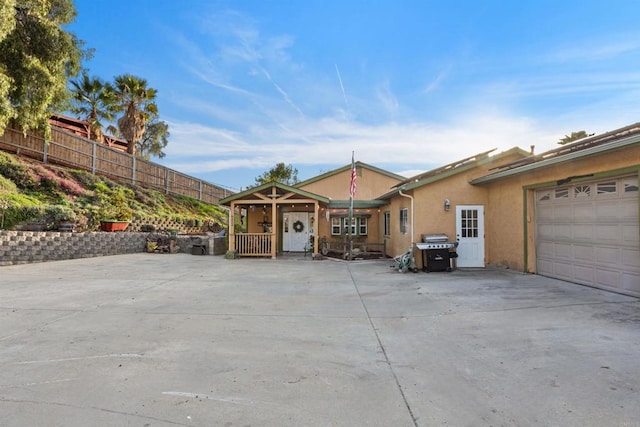 view of front of property with stucco siding, an attached garage, concrete driveway, and fence