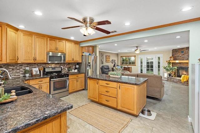 kitchen with a sink, ornamental molding, a kitchen island, and stainless steel appliances