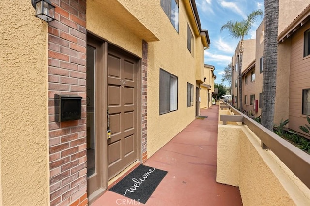 view of exterior entry with a balcony and stucco siding