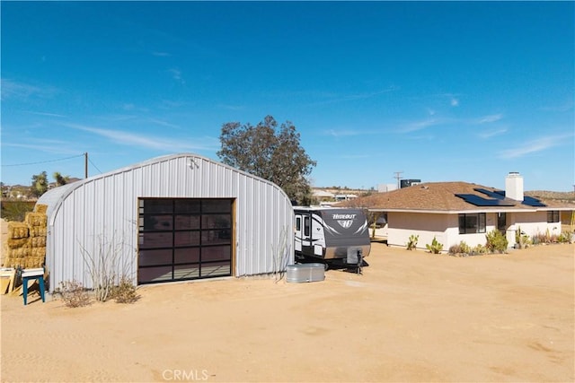 view of outdoor structure featuring dirt driveway, solar panels, and an outdoor structure