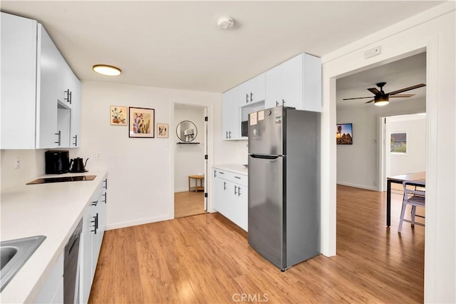 kitchen with light countertops, freestanding refrigerator, white cabinetry, ceiling fan, and light wood-type flooring