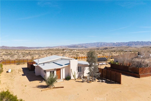 exterior space with view of desert, a fenced backyard, a mountain view, and stucco siding