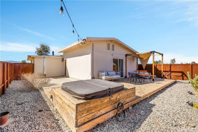 back of house with a covered hot tub, a fenced backyard, and a wooden deck