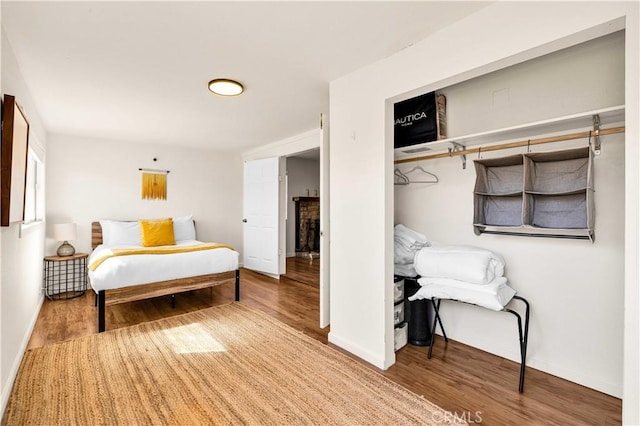 bedroom featuring a fireplace, baseboards, and wood finished floors