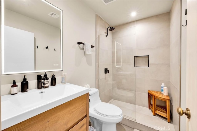 full bath with toilet, tiled shower, vanity, and visible vents