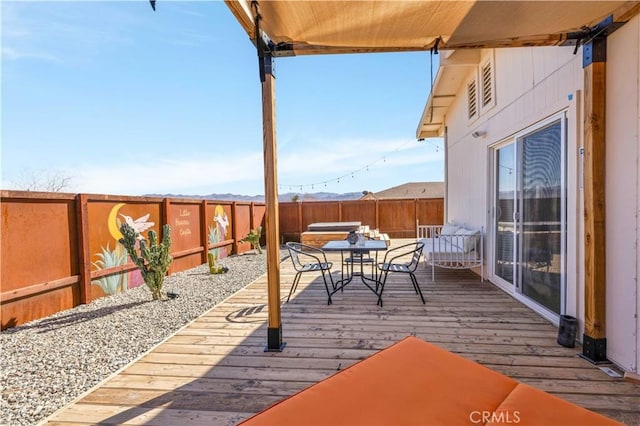 wooden deck featuring outdoor dining space and a fenced backyard