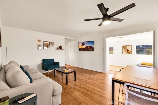 living room with ceiling fan, light wood finished floors, and baseboards