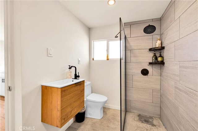 bathroom with vanity, a tile shower, and toilet