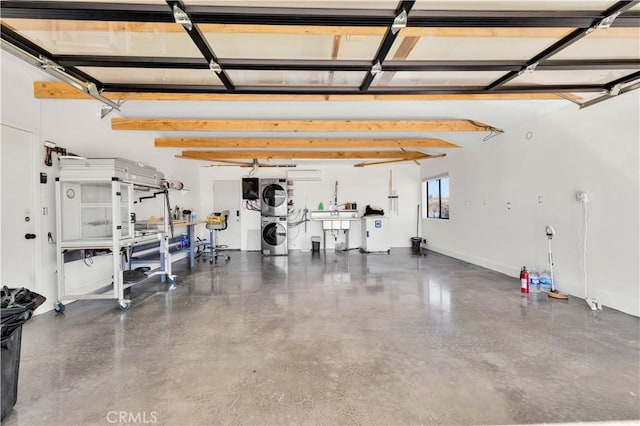 garage featuring baseboards and stacked washer / drying machine