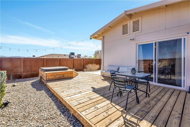 deck with a covered hot tub, a fenced backyard, and outdoor dining space