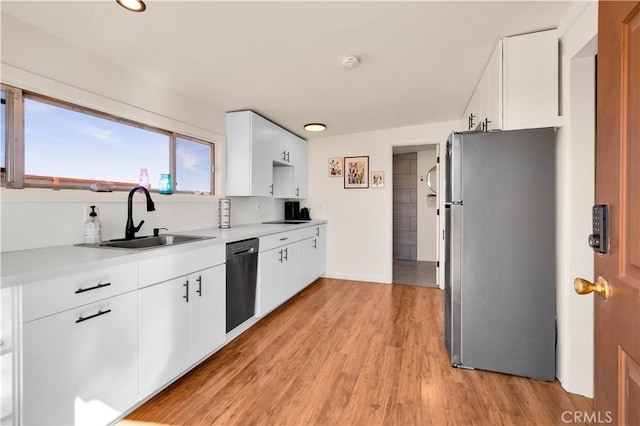 kitchen with a sink, light countertops, light wood-type flooring, freestanding refrigerator, and dishwasher