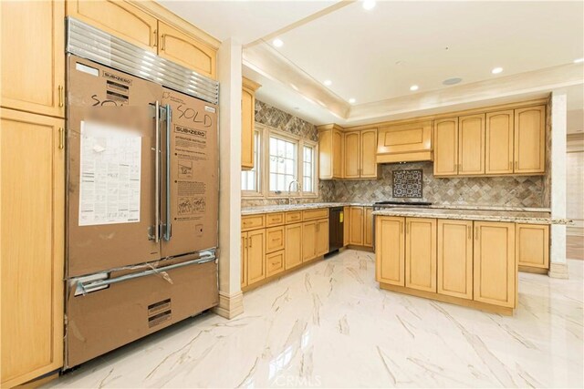 kitchen with marble finish floor, appliances with stainless steel finishes, decorative backsplash, light brown cabinetry, and a tray ceiling