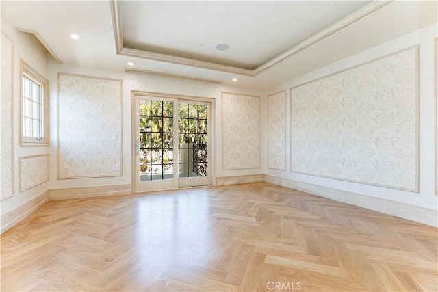 empty room with a raised ceiling, a wealth of natural light, and a decorative wall