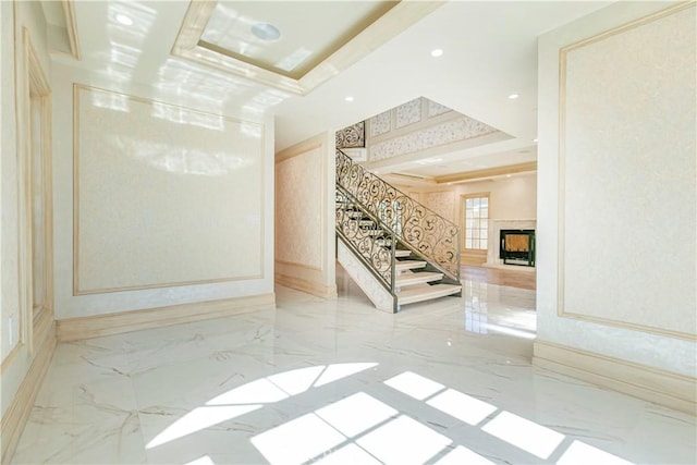 empty room with recessed lighting, a fireplace, marble finish floor, stairway, and a tray ceiling