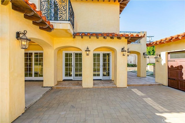 back of house featuring french doors, a patio area, a tiled roof, and stucco siding