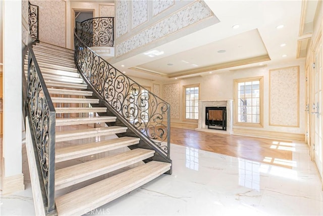 stairs featuring recessed lighting, marble finish floor, a raised ceiling, and a fireplace