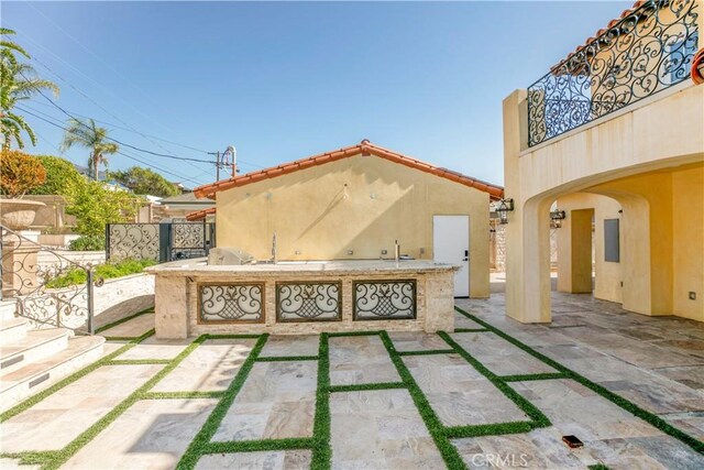 view of patio / terrace featuring an outdoor kitchen, fence, and a balcony