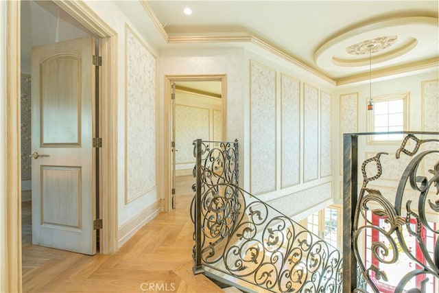 corridor featuring a tray ceiling, crown molding, and an upstairs landing