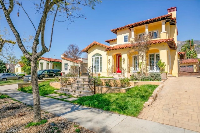 mediterranean / spanish-style house with french doors, a tile roof, and stucco siding