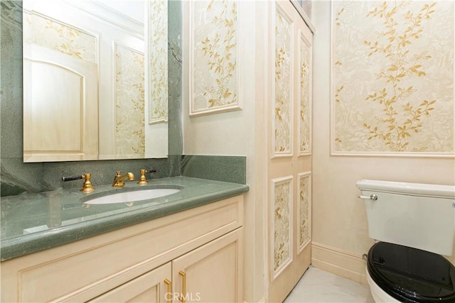 bathroom featuring baseboards, vanity, and toilet