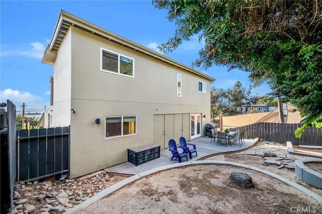 rear view of house featuring fence and stucco siding