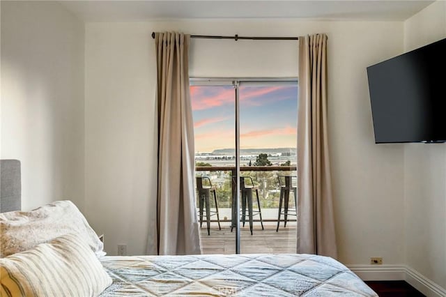 bedroom with access to outside, wood finished floors, and baseboards