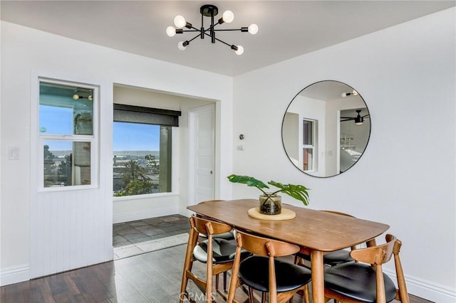 dining area with baseboards, dark wood-type flooring, and a notable chandelier