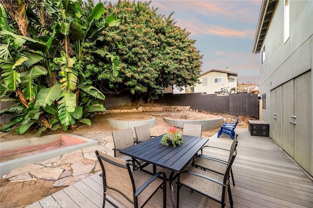 deck at dusk with outdoor dining space and a fenced backyard