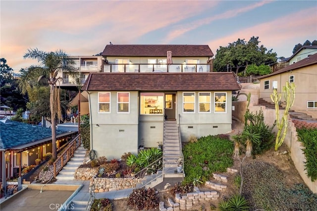 view of front of house featuring stairway, crawl space, a shingled roof, and stucco siding