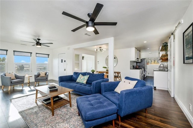 living area with baseboards, visible vents, dark wood-type flooring, and ceiling fan with notable chandelier