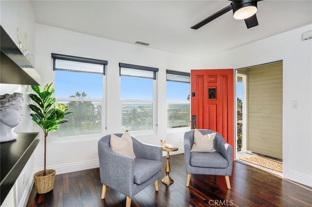 living area with a ceiling fan, wood-type flooring, visible vents, and baseboards