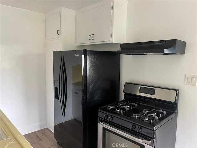 kitchen featuring light wood-style flooring, under cabinet range hood, black fridge with ice dispenser, white cabinets, and stainless steel range with gas cooktop