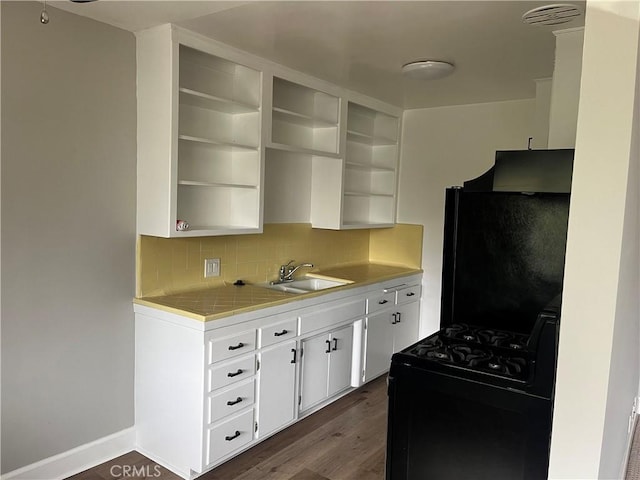 kitchen with black appliances, under cabinet range hood, open shelves, and a sink