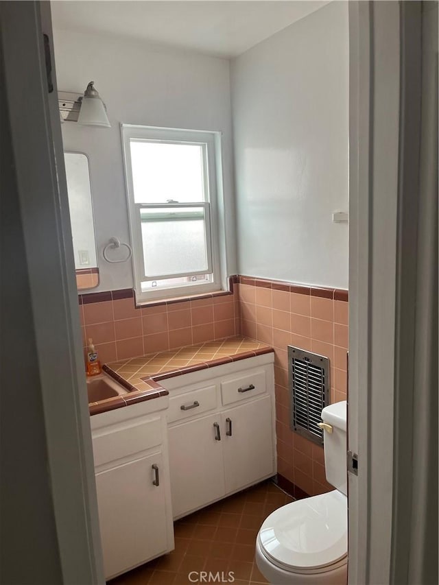 bathroom with wainscoting, tile walls, toilet, and tile patterned floors