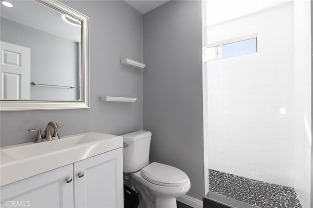 full bath with a tile shower, vanity, and toilet