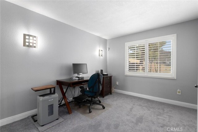 carpeted office space with a textured ceiling and baseboards