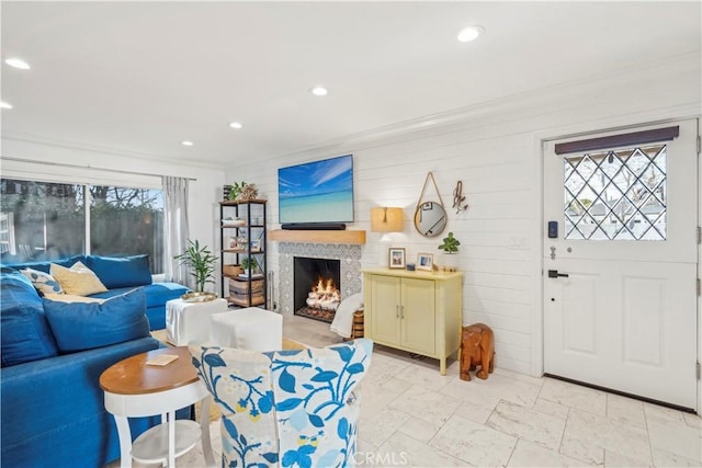 living room featuring a warm lit fireplace, ornamental molding, and recessed lighting