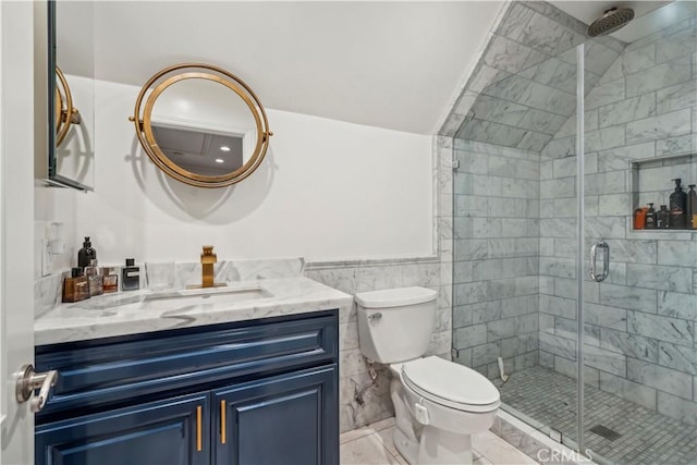 bathroom with a stall shower, toilet, vanity, and tile walls