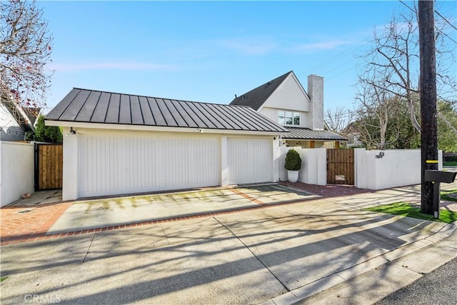 garage featuring a gate, fence, and driveway