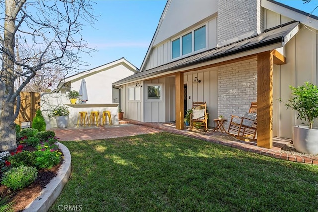 back of property with a patio area, outdoor dry bar, board and batten siding, and brick siding