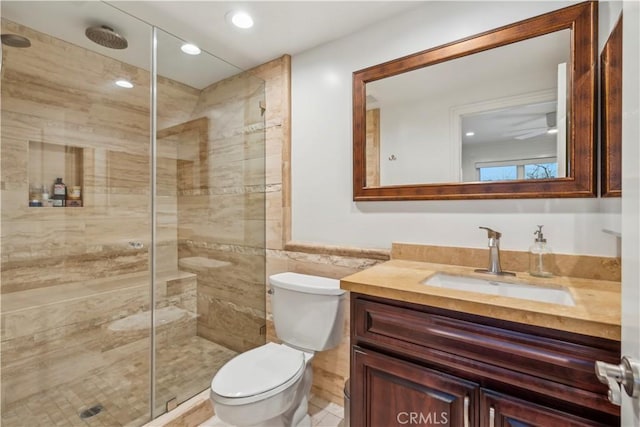 bathroom featuring toilet, a shower stall, tile walls, and vanity