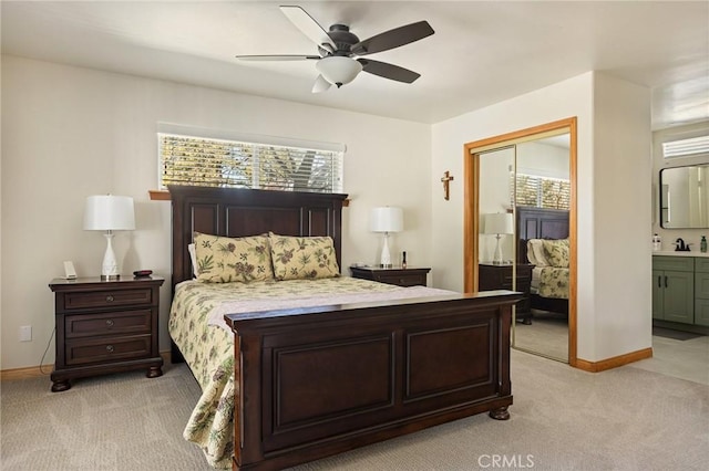 bedroom with light carpet, a sink, baseboards, a closet, and ensuite bath