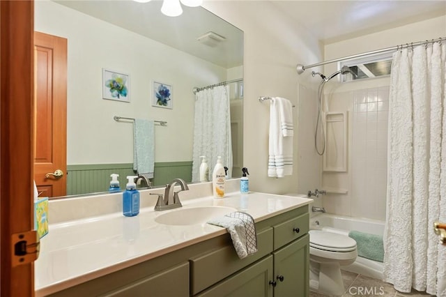 bathroom with toilet, shower / bath combo with shower curtain, wainscoting, vanity, and tile patterned floors