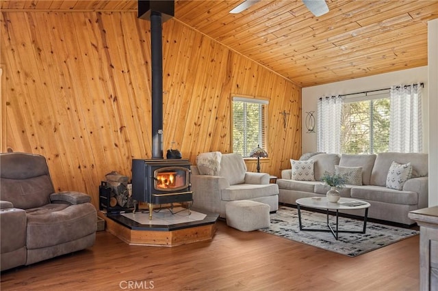 living area featuring wood ceiling, wood finished floors, a wood stove, vaulted ceiling, and wood walls