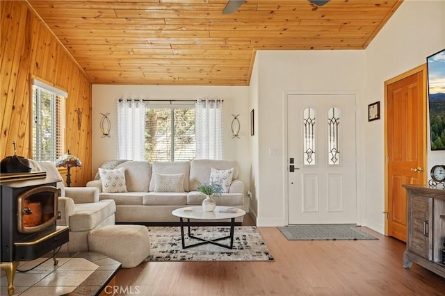 living area with lofted ceiling, a wood stove, wood ceiling, and wood finished floors