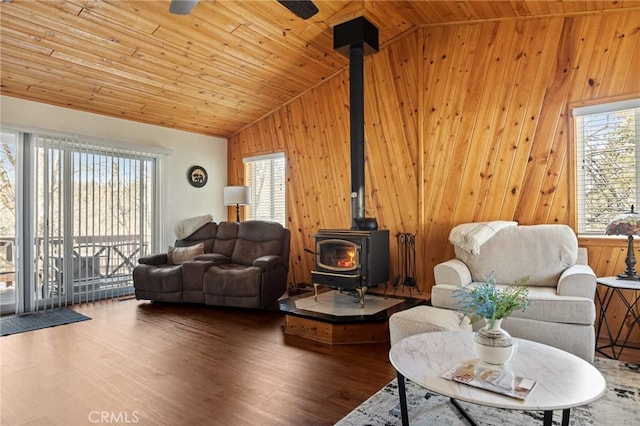 living room featuring vaulted ceiling, wooden ceiling, wood finished floors, and a wood stove