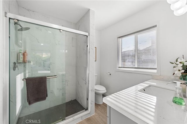 full bath with a marble finish shower, vanity, toilet, and wood finished floors