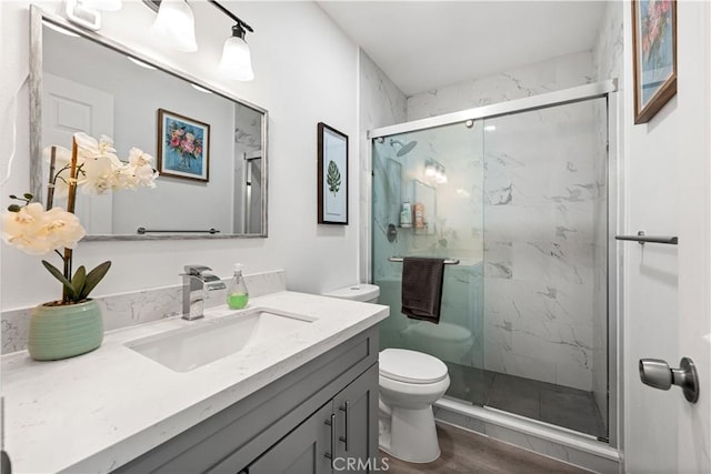 full bath with vanity, wood finished floors, a marble finish shower, and toilet