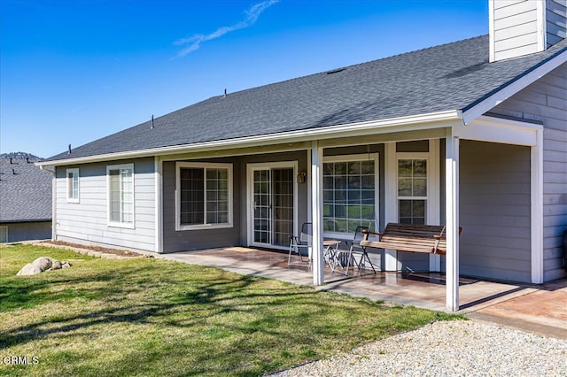 back of house featuring a shingled roof, a patio area, and a yard